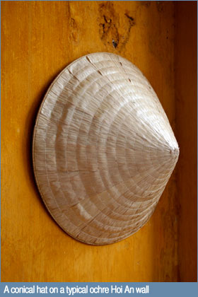 A conical hat on a typical ochre Hoi An wall A conical hat on a typical ochre Hoi An wall
