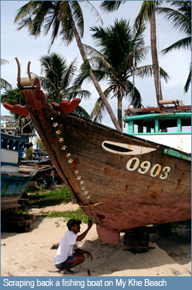 Scraping back a fishing boat on My Khe Beach, Da Nang, Vietnam