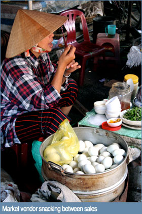 Photo of market vendor snacking between sales in Hoi An, Vietnam Photo of market vendor snacking between sales in Hoi An, Vietnam